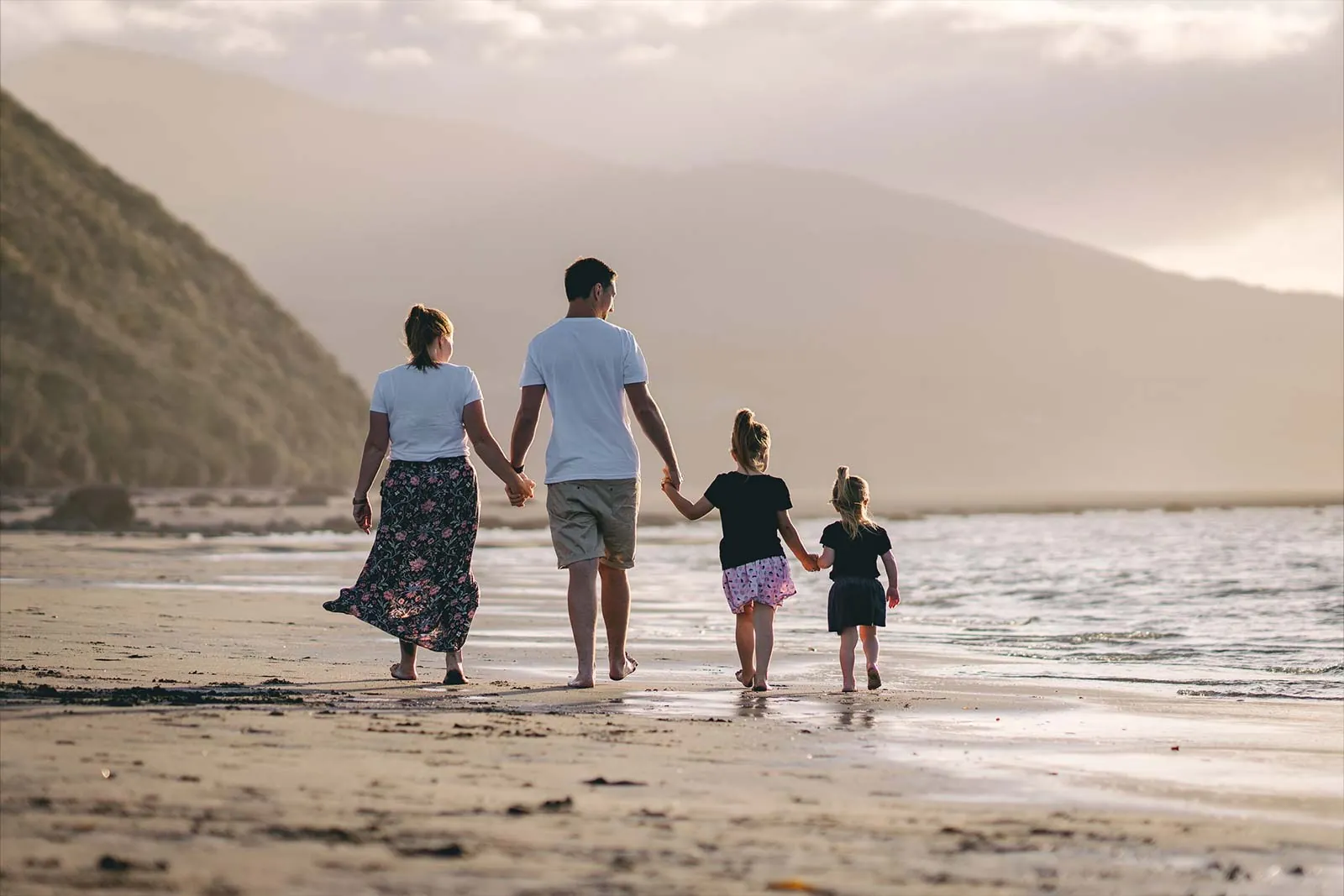 Family walking along Raglan beach at sunset