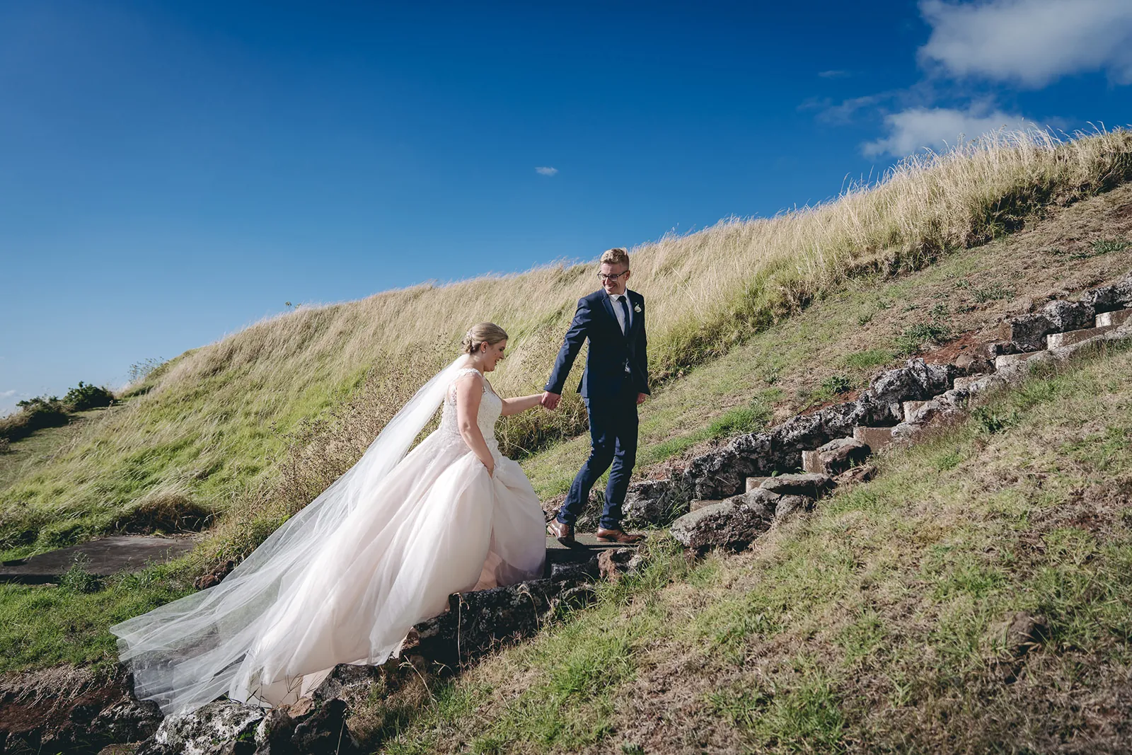 Bride and groom walking together on a hillside