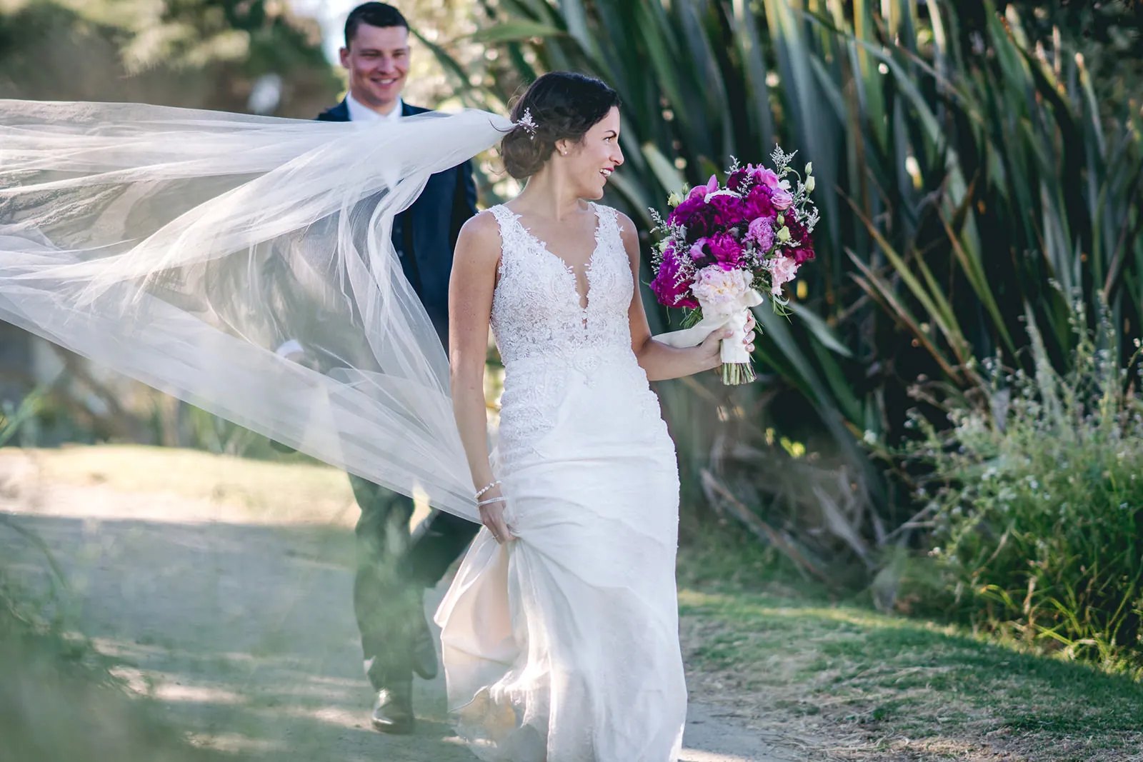 Bride with a windswept veil and colourful bouquet